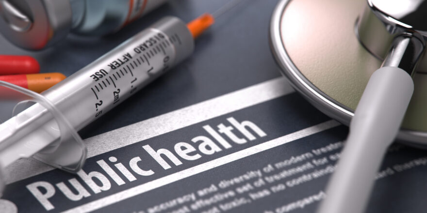 Public Health. Medical Concept with Blurred Text, Stethoscope, Pills and Syringe on Grey Background. Selective Focus.